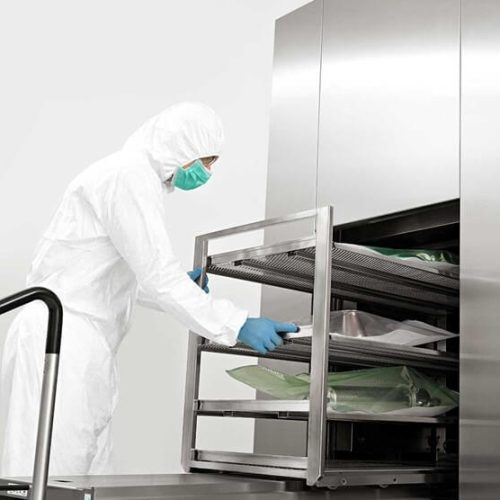 Autoclave being used by an operator in a sterile facility. The trolley is pulled out with load items displayed