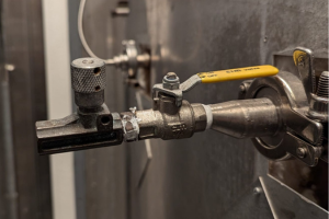 A yellow hand operated valve sits attached to pipework at the back of an autoclave.